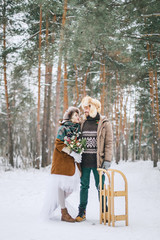 Newlyweds walk in the Park in winter. Man and woman standing with sledge.