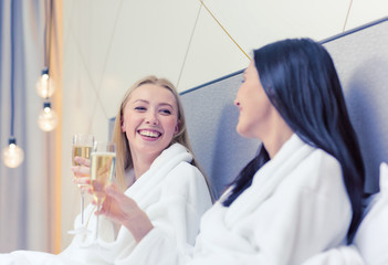 Poster - smiling girlfriends with champagne glasses in bed