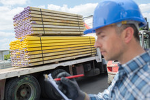 Man With Clipboard Next To Lorry Delivering Timber