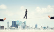 © adam121 - Business concept of risk support and assistance with man balancing on rope