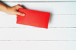 Red Envelope or red packet for Chinese New Year Gifts held in hand on the white wooden plank background, Traditional Celebration Chinese New Year.