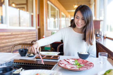 Poster - Woman having roasted sliced of beef in japanese yakiniku