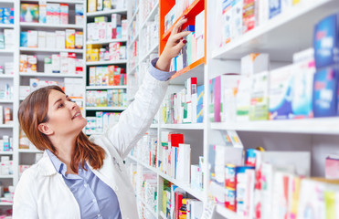 Wall Mural - Photo of a professional pharmacist checking stock in an aisle of a local drugstore.