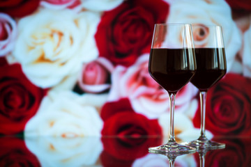 Two glasses of red wine against bokeh background with sparkles and roses. Very shallow depth of field. Selective focus, copy space