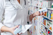 Woman pharmacist holding prescription checking medicine in pharmacy - drugstore.