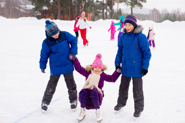 two boys helps girl learn to skate