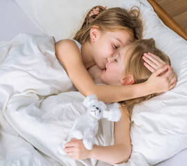 two little sisters hugging in bed