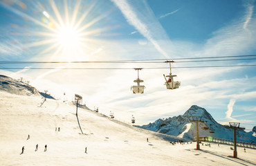 Panoramic view of ski resort glacier and chair lift in french alps - Winter vacation and sport travel concept - Snowboard season opening and people having fun on mountain - Warm afternoon color tone