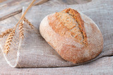 Fototapeta Kuchnia - fresh loaf of bread on a linen napkin, food on vintage table
