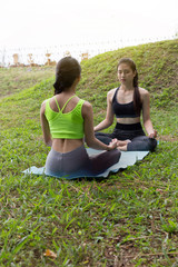 young woman meditates while practicing yoga outdoor in park,  re