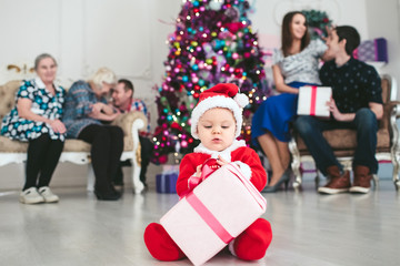 big family and child in a suit of Santa Claus sitting by the Christmas tree