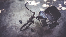 Retro Collection Of The Rusty Small Metal Tricycle (3 Wheels) On A Concrete Floor.  (vintage Style)