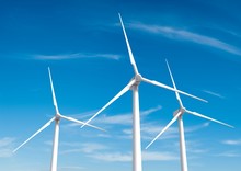 Three White Wind Turbine Generating Electricity On Blue Sky