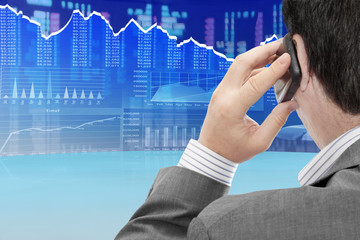 Fototapete - Man on a phone analyzing financial data and charts 