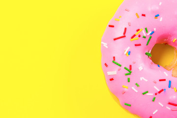 Pink round donut on yellow background. Flat lay, top view.