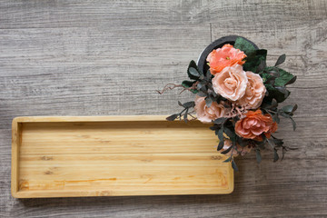 Top view of empty wooden square tray and artificial flower backg