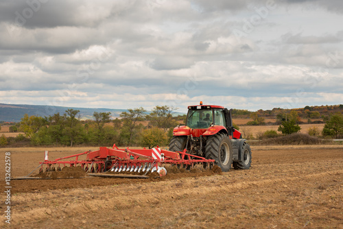 Vászonkép Farmer in tractor preparing land with seedbed cultivator