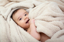 Cute Baby Boy In Bed Under A Fluffy Blanket