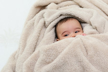 Cute Baby Boy In Bed Under A Fluffy Blanket