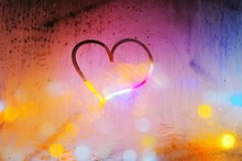 Abstract Background - Heart Painted On A Misted Window On The Background Of Colorful City Lights At Night