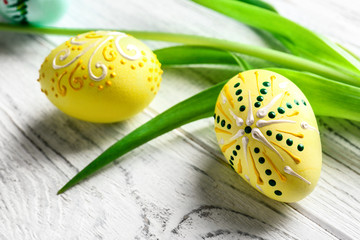 Wall Mural - Beautiful Easter eggs and fresh leaves on white wooden background, closeup