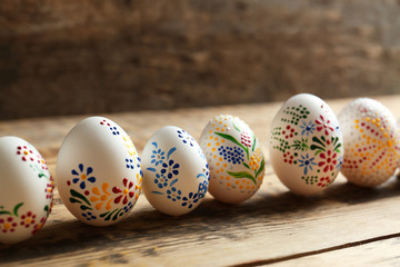 Wall Mural - Colourful Easter eggs with floral ornament in a row on wooden background, closeup