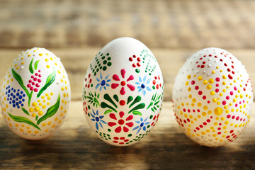 Wall Mural - Colourful Easter eggs with floral ornament in a row on wooden background, closeup