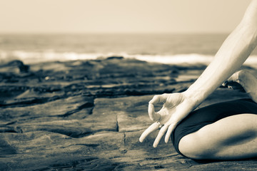 Close up of a woman practicing yoga on the rocks by the sea