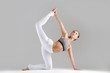 © fizkes - Young attractive woman practicing yoga, stretching in Bird dog exercise, tiger pose, working out wearing sportswear, white pants, bra, indoor full length, isolated against grey studio background