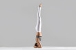 © fizkes - Young attractive woman practicing yoga, standing in headstand exercise, salamba sirsasana pose, working out wearing sportswear, white pants, bra, indoor full length, isolated, grey studio background