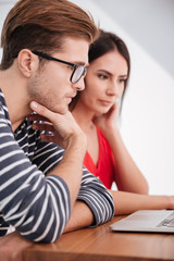 Wall Mural - Vertical image of young couple by the table with laptop