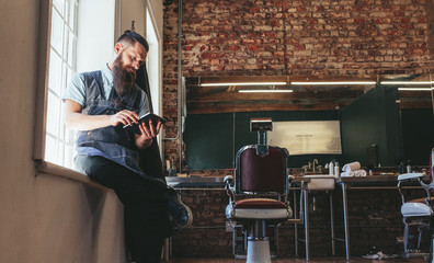 Hairstylist using digital tablet at his shop