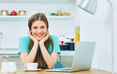 Wall Mural - smiling woman with laptop working in kitchen area.