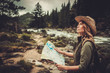 © Nejron Photo - Woman hiker, searching right direction on map near wild mountain river