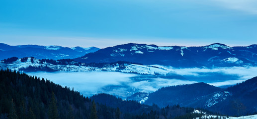 Beautiful view of the blue winter mountains and hills in Carpathians on the sunrise