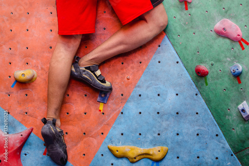 Cuadros en Lienzo Man climbing artificial boulders in gym, close-up view of legs with special shoe