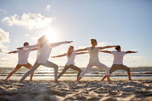 Group Of People Making Yoga Exercises On Beach