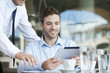 © PhotoAlto - Businessman showing colleague how to use digital tablet