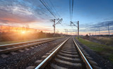Fototapeta  - Railway station against beautiful sunny sky. Industrial landscape with railroad, blue sky and colorful clouds at sunset . Railway junction in the evening. Heavy industry. Cargo shipping. Travel