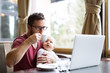 © Halfpoint - Man with notebook in cafe drinking coffee, holding his son