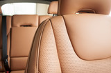 Part of red leather car seat with the unfocused car interior on the background