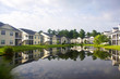Southern residential neighborhood. Background with a modern neighborhood with buildings for vacation rental around the pond. Houses and trees reflected in the tranquil water during cloudy morning.
