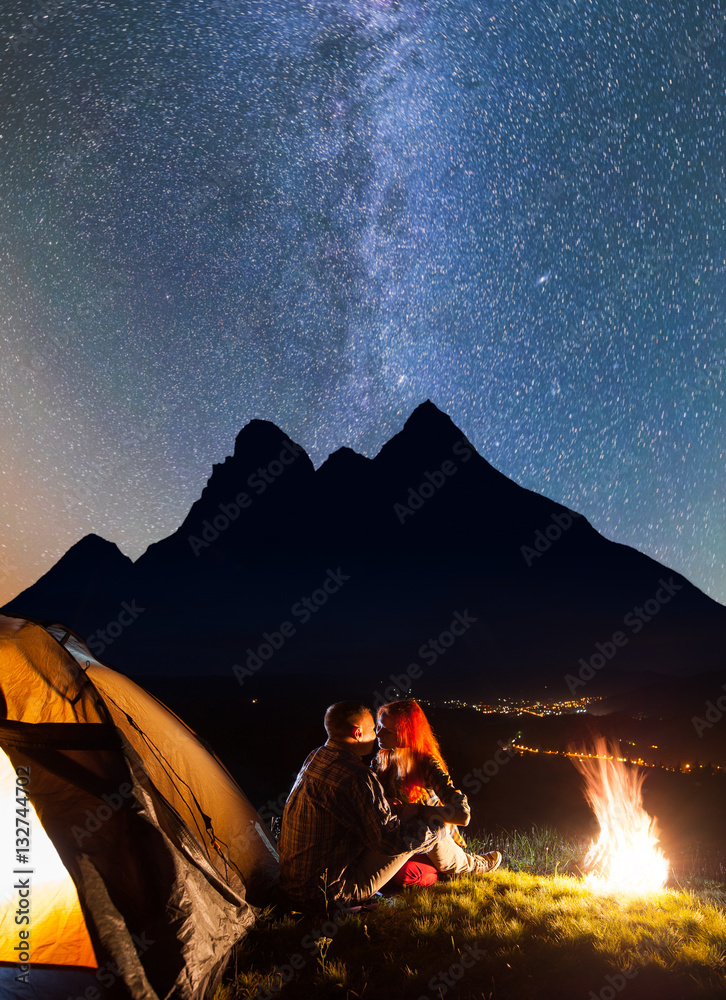 Night camping. Tourist couple - girl and guy sitting and kissing near a ...