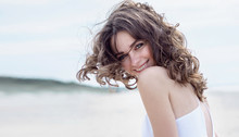 Happy Woman On The Beach. Portrait Of The Beautiful Girl Close-up, The Wind Fluttering Hair. Spring Portrait On The Beach. Young Pretty Girl. Young Smiling Woman Outdoors Portrait. Close Portrait.