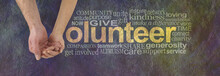 We Can Volunteer Together - Male Hand Cupped By A Female Hand Making The V Of VOLUNTEER Surrounded By A Word Cloud On A Rustic Dark Colored Stone Effect Background
