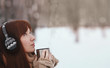 © estradaanton - Winter. Woman with red hair wearing ear muffs. Girl drinking hot tea or coffee  iron insulated cup