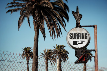 Wall Mural - aged and worn vintage photo of surfing sign with palm trees 