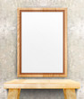 Blank wooden photo frame hanging at clean concrete wall on wood
