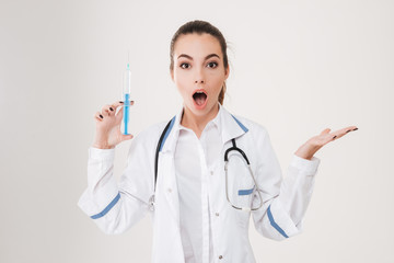 Poster - Shocked young woman doctor with syringe holding copyspace on palm