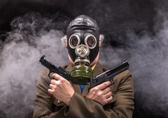 Portrait of a soldier in a gas mask with a gun on a black background isolated